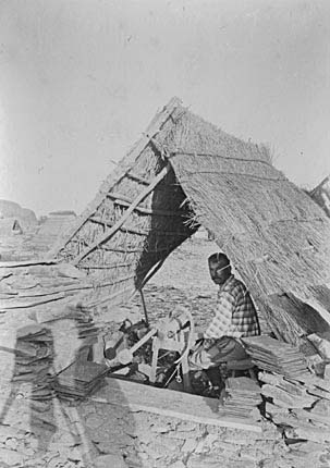 Photograph: Slate dresser at work in his straw cabin, Angers, France.
